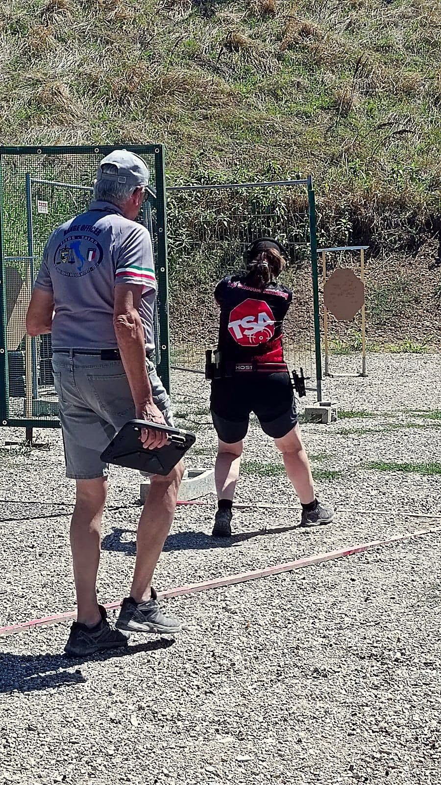 Tiratrice con pistola su uno stage, seguita dal range officer